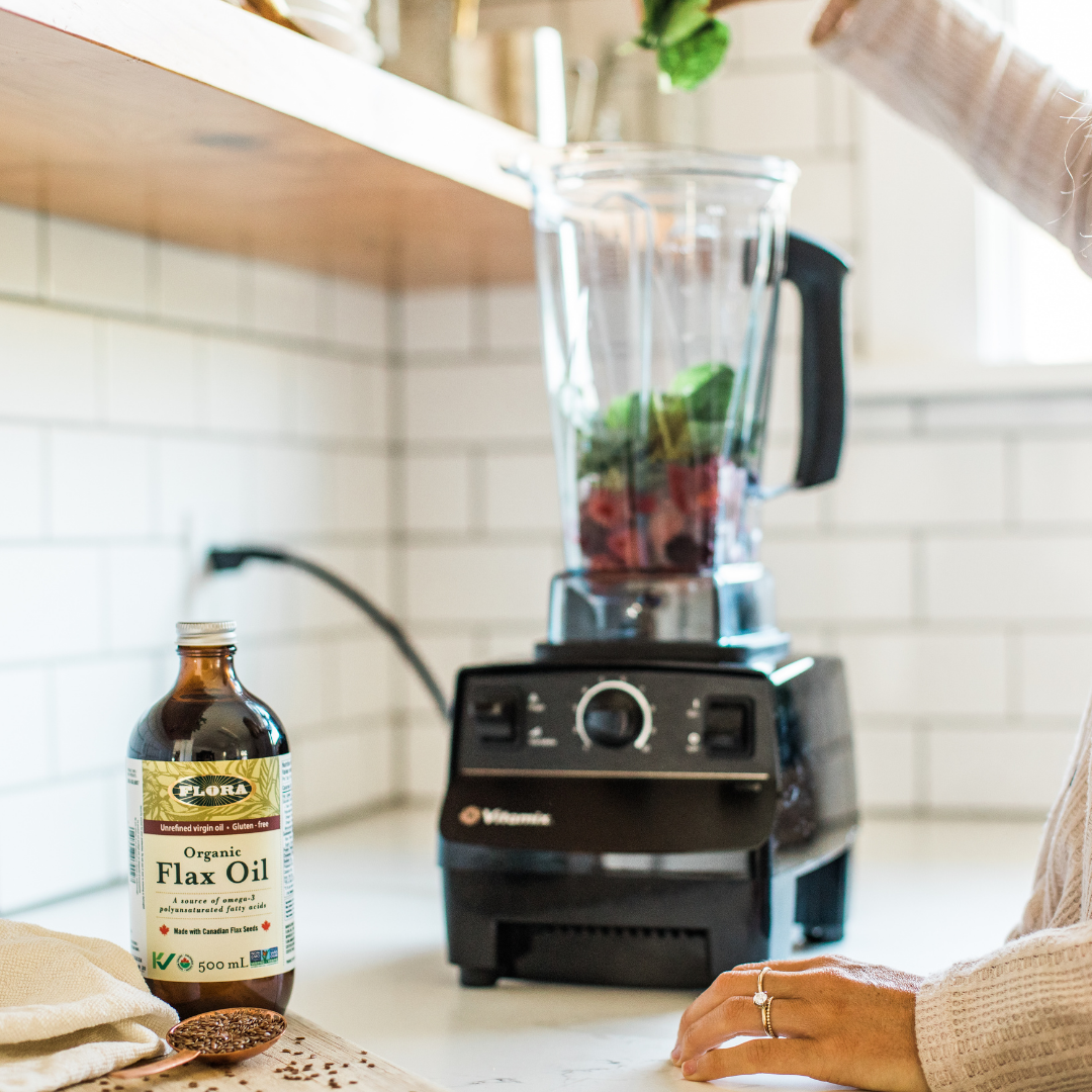 organic flaxseed oil being added to smoothie with flaxseeds, spinach, raspberries, and blackberries