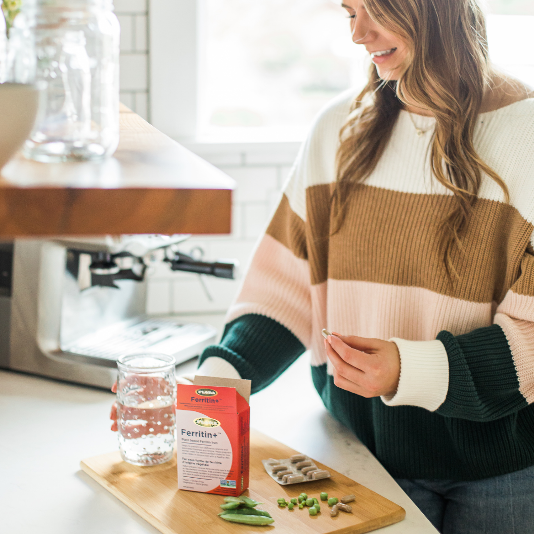 woman taking ferritin iron supplement with snap peas and water